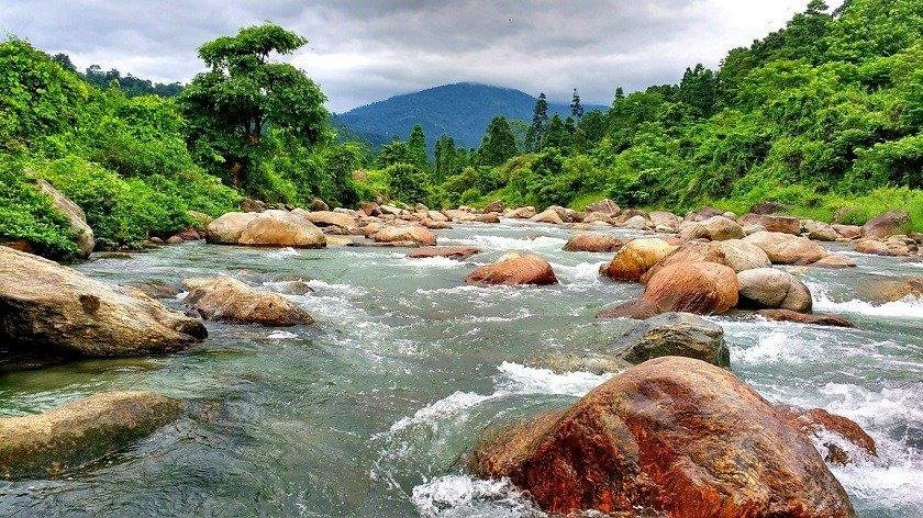 Popular riverside picnic and camping destination surrounded by rocks, forests, and hills.